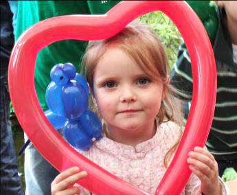 kleines mdchen mit ballonherz beim strassenfest